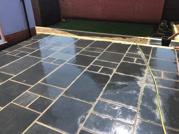 Wet black limestone patio slabs laid in a random pattern