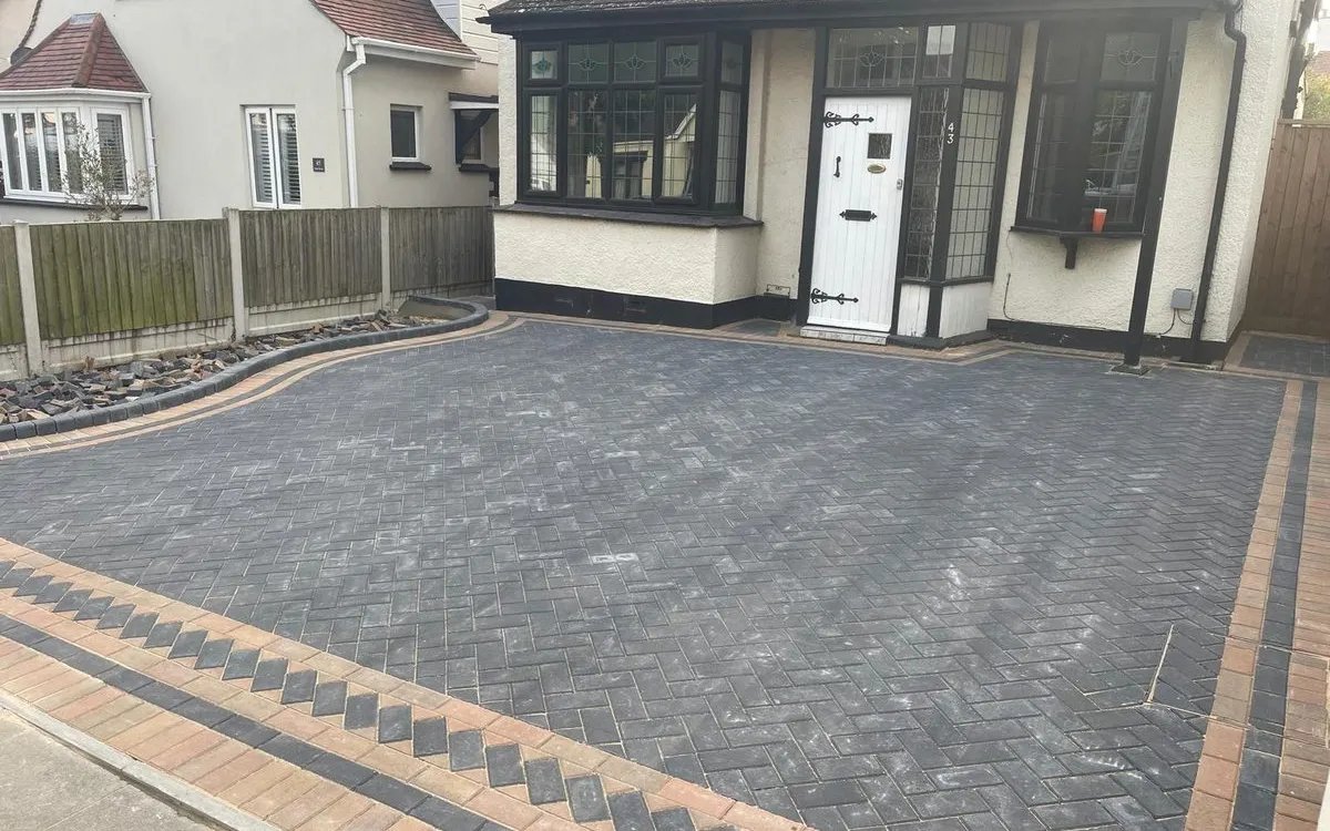 The same house with a charcoal herringbone block paving driveway and a buff chevron border