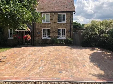 The same cottage with a new buff herringbone block paving drive and a red border