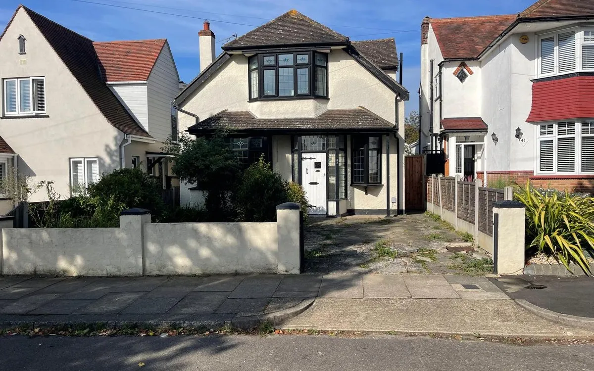 Overgrown front garden with cracked concrete slabs before the new driveway