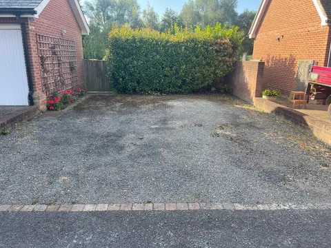 Tired gravel drive in front of a brick garage before the work