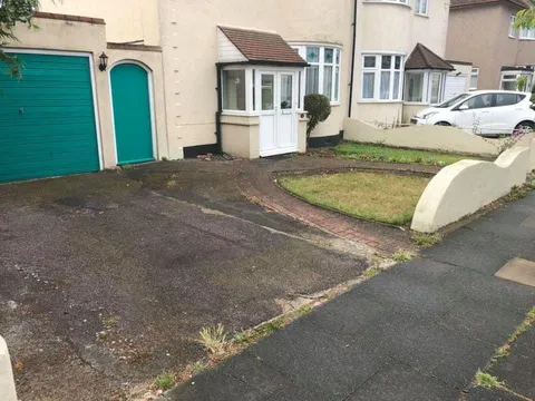 Worn tarmac drive with curved white walls in front of a 1930s semi before the work