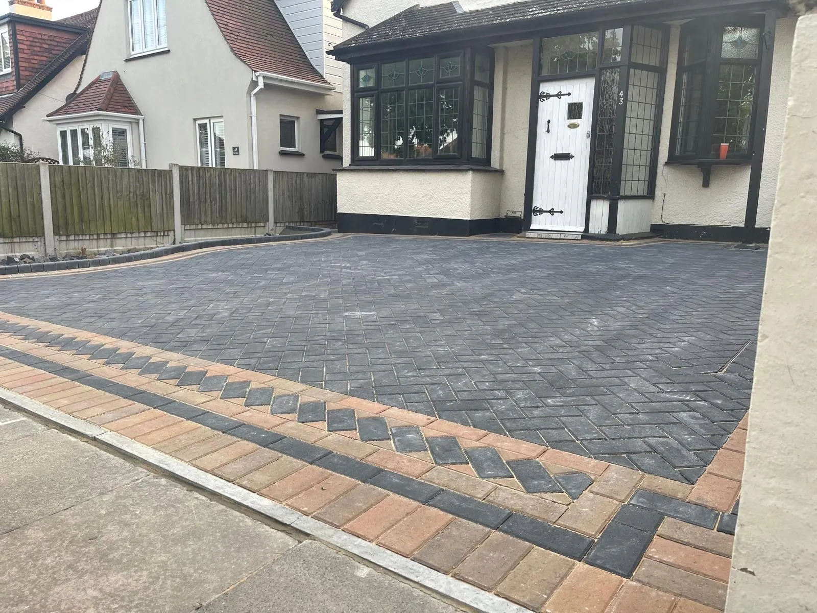 Charcoal herringbone block paving driveway with a buff and charcoal chevron border in front of a 1930s detached house, laid by First4Driveways