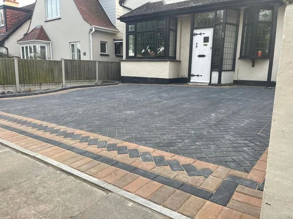 Charcoal herringbone block paving driveway with a buff and charcoal chevron border in front of a 1930s house
