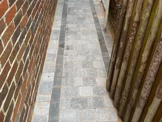 Grey block paving garden path with a charcoal border running down a side passage