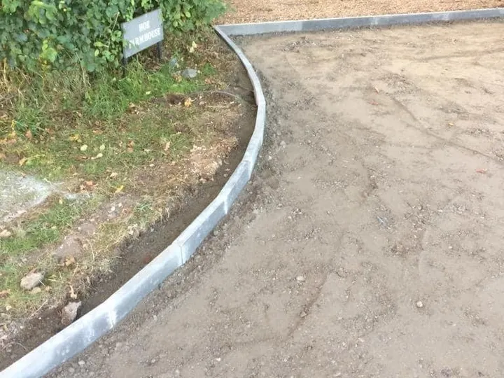 Concrete edge kerbs set on a curve along a dug-out drive before the sub-base and blocks go down