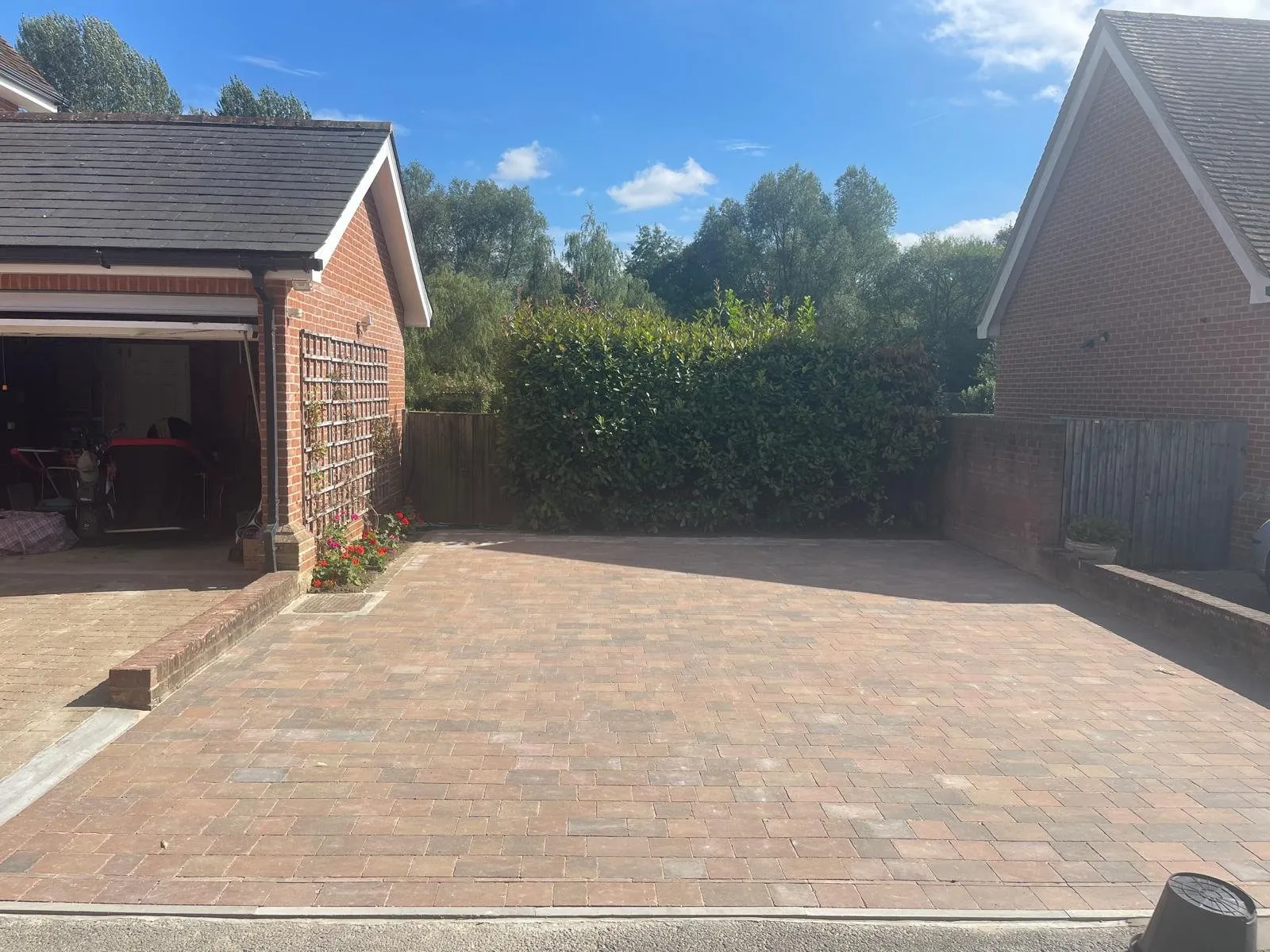 Herringbone block paving driveway with a soldier border and a raised brick bed in front of a red-brick garage, laid by First4Driveways