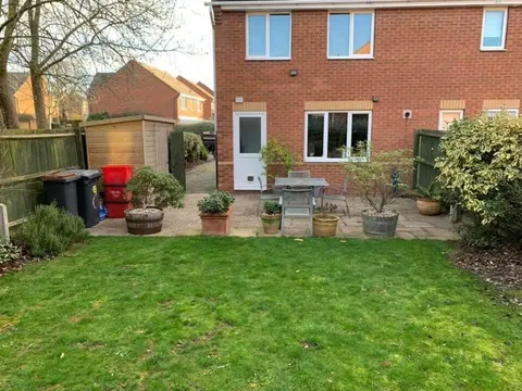 Back garden with a worn lawn and an old patio before the work
