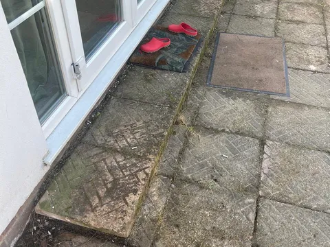Old concrete slabs and stacked blocks outside French doors before the work