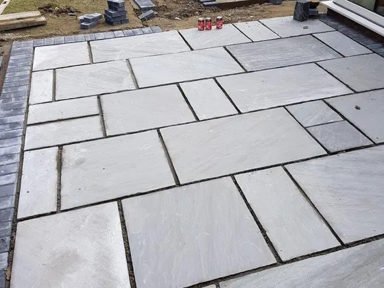 Large-format grey and buff slab patio laid in a running pattern outside bifold doors