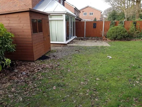Lawn and a shed beside a conservatory before the patio