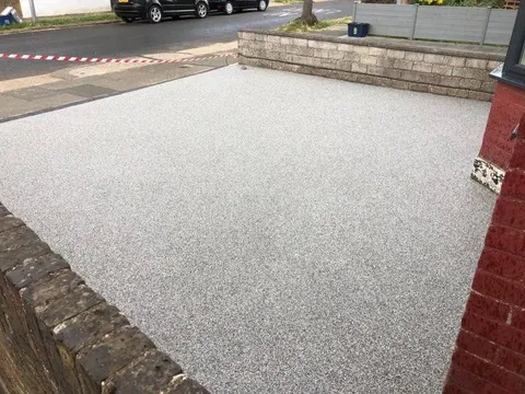 New silver resin bound driveway with a charcoal border in front of the red-brick house