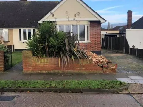 Old concrete slabs and a brick wall in front of a bungalow before the work