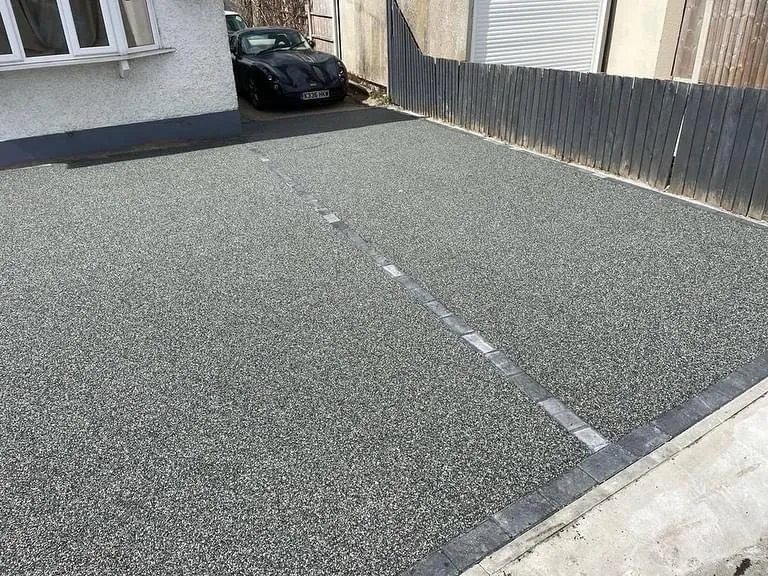 Silver-grey resin bound driveway with charcoal block edging at a white bungalow, laid by First4Driveways
