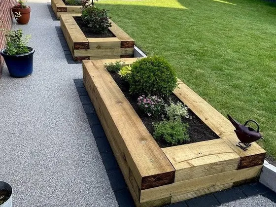 Planted timber sleeper raised beds beside a grey resin path