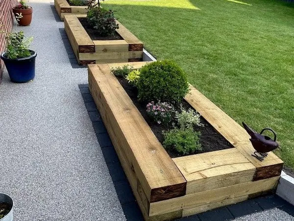 Planted timber sleeper raised beds beside a grey resin path