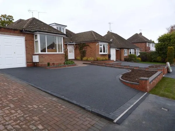 Black tarmac driveway with a red block paving apron at the pavement
