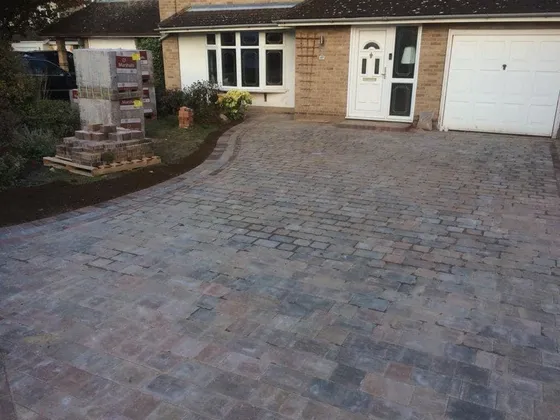 Brindle Tegula-style cobble block paving driveway with a red border in front of a white garage door